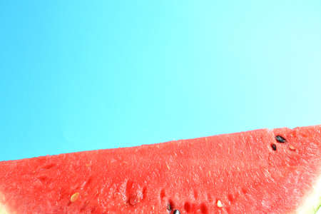 Fresh sliced watermelon isolated on blue background. Ripe red watermelon. Minimal creative concept. Place for text. Bright healthy summer food. Half watermelonの写真素材
