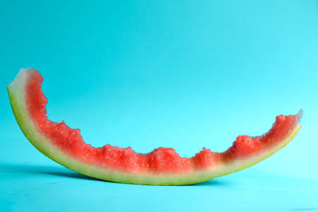 Fresh sliced watermelon isolated on blue background. Eaten watermelon. Peel. Minimal creative concept. Place for text. Bright healthy summer food.の写真素材