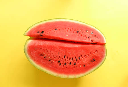 Fresh sliced watermelon isolated on yellow background. Ripe red watermelon. Minimal creative concept. Place for text. Bright healthy summer food.の写真素材