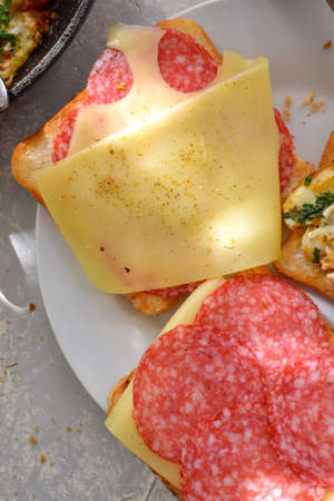 Delicious fast food breakfast. Crispy Toast with cheese and sausage. Sandwich in a white plate Light...