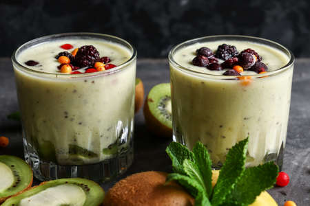 Yogurt with berry and kiwi in a glass. Fruit and berry smoothie. Milkshake with kiwi, raspberry, blueberry and banana Healthy food. Dark background. Copy space.の写真素材