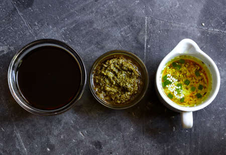 Assortment of sauces. Herbal oil, soy sauce and pesto in bowls. Top view.
