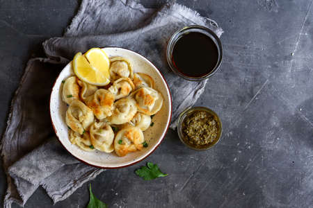 Dumplings with meat filling. Top view. Dark background. Fried dumplings. The concept of a delicious lunch or dinner.の写真素材