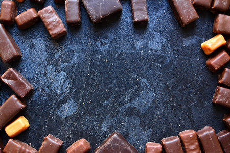 Assortment of chocolates. Candies on a dark bluish background. Top view place for text. Dark chocolate. Chocolate bars.の写真素材