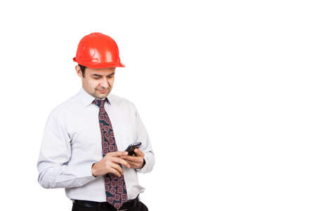 man engineer in a red helmet with a mobile phone in handの写真素材