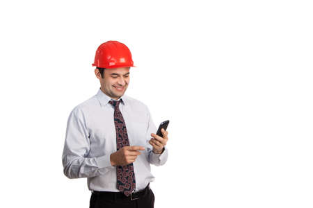 man engineer in a red helmet with a mobile phone in handの写真素材