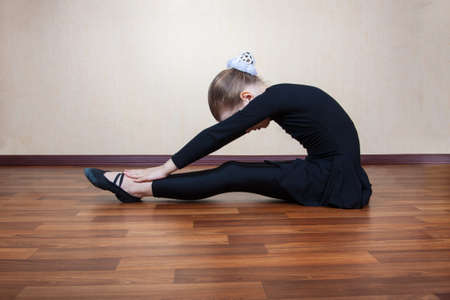 little girl gymnast sitting on the floorの写真素材
