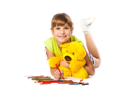 cheerful girl draws pencil lying on the floorの写真素材