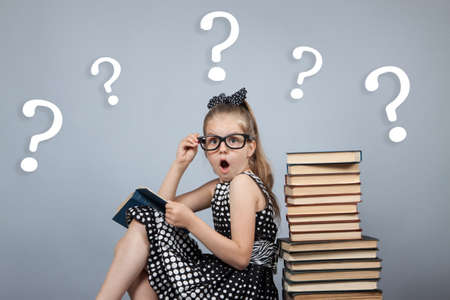 smart girl with glasses reading a book and is very surprisedの写真素材