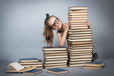 smart girl with a stack of books. Girl with glasses reading a bookの写真素材
