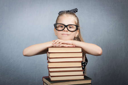 smart girl with a stack of books. Girl with glasses reading a bookの写真素材