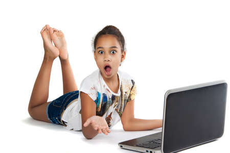 Dark-skinned teen girl with a laptop lies. Girl surprised.