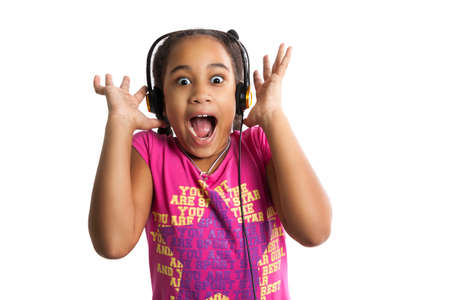 Surprised dark-skinned girl in headphones screaming. Little girl in shockの写真素材