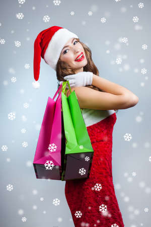 Young beautiful girl  with shopping bags. woman in a Santa Claus hat. Christmas portraitの写真素材