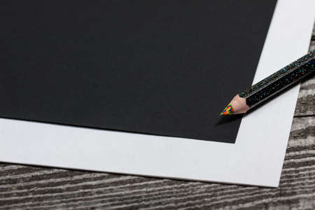 Blank black paper and colorful pencil on the wooden table. View from aboveの写真素材