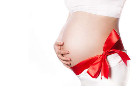 Pregnant Woman Belly with Red Ribbon and Big Bow. Expecting Baby Pregnancy Concept