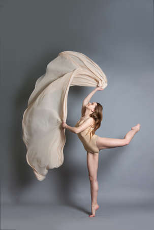 beautiful young girl dancing with brightly colored fabrics. Flying fluttering fabric. Girl throws a light fabricの写真素材
