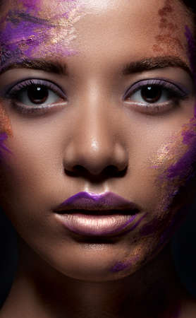 A beautiful dark-skinned woman with paint on his face. Beauty, fashion, portrait. Creative make-up...