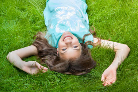 pretty teen girl lying on the grass. laughter, joy, positive human emotionsの写真素材