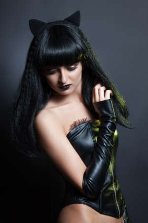 fashion beauty portrait of a beautiful young Sexy woman in leather clothes with koshachmi ears on the hair.の写真素材