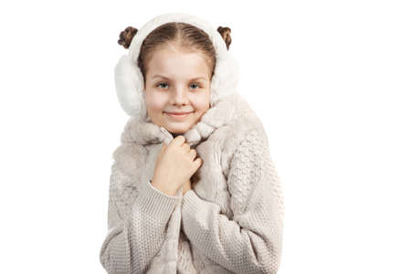 cute little girl in warm clothes on white background. girl in fur headphones wrapped in a winter jacketの写真素材