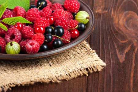 Fresh ripe berries in the bowl on the old wooden table. Useful natural food. Fruits and berries