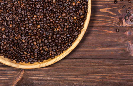 large wooden platter with coffee beans on the table. Horizontal top view. Empty space to place textの写真素材
