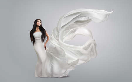 beautiful young girl in flying white dress. Flowing fabric. Light white cloth flying in the windの写真素材