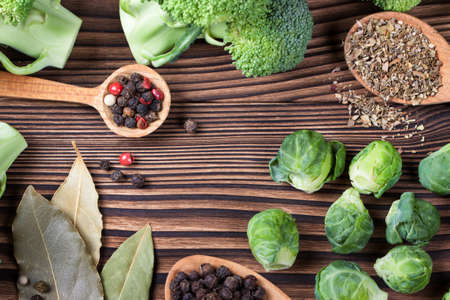 beautiful still life with herbs and spices on a wooden table. Horizontal top view. broccoli, brussels sprouts, bay leaf and spices for soupの写真素材