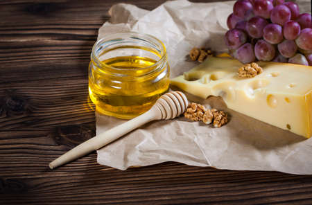 Cheese, walnuts and grapes on a wooden backgroundの写真素材