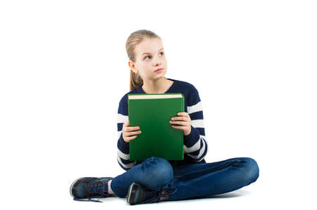 Pretty teen girl sitting on the floor with a book in his hands. Girl looking away