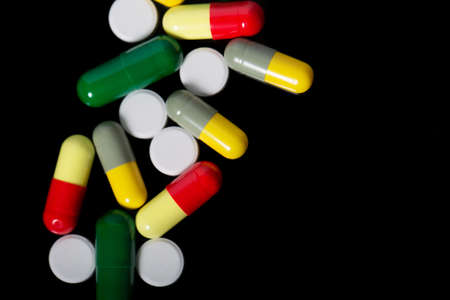Assorted pharmaceutical medicine pills, tablets and capsules over black background. close-up. macroの写真素材