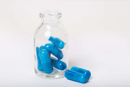 Blue pills in pill bottle on white backgroundの写真素材