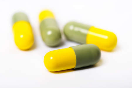 Pills close-up. Yellow-green capsules on a white backgroundの写真素材