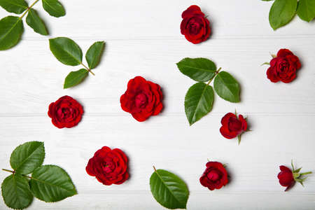 Flower pattern made from red roses and leaves. White wooden table. View from aboveの写真素材
