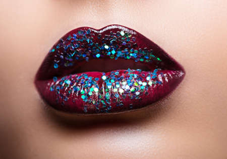 Beautiful female lips with magnificent make-up close-up. Red lips are covered with large sparklesの写真素材