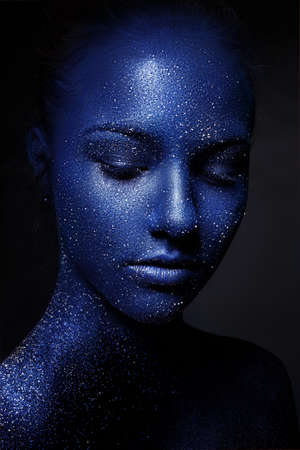 portrait of young beautiful girl. face painted with blue paint and glitter. eyes closedの写真素材
