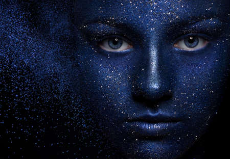 beautiful girl face vakrasana blue paint with glitter. The effect of the collapse. the flying...