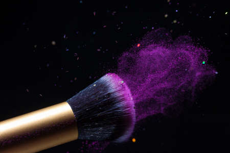 Cosmetics makeup brush and powder dust explosion background. Sequins flyの写真素材