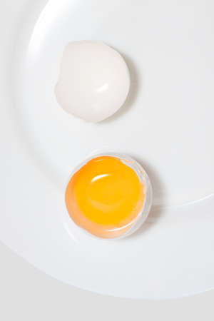 close-up of chicken egg on a white plate. The shell split. Two halves. Horizontal top viewの写真素材