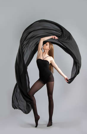 beautiful young girl dancing with black cloth. flying fabric. Gray backgroundの写真素材