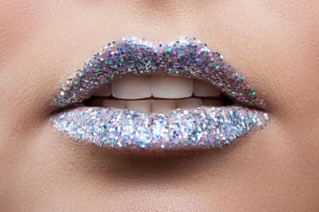 Beautiful female lips closeup. Lips in sequins. Metal sequins. Glitter. macro. Semi-open mouthの写真素材