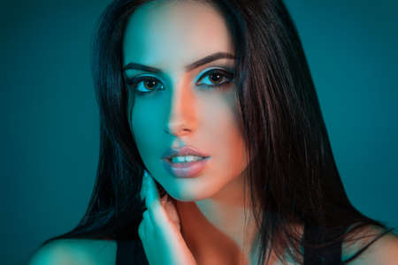 Creative Studio portrait of beautiful female model close-up. The blue lights. Looking at the cameraの写真素材