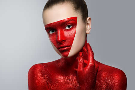 beauty fashion portrait of a young girl. Face and hands painted with red paint with glitter. the Red particles of the metal powder. tinselの写真素材