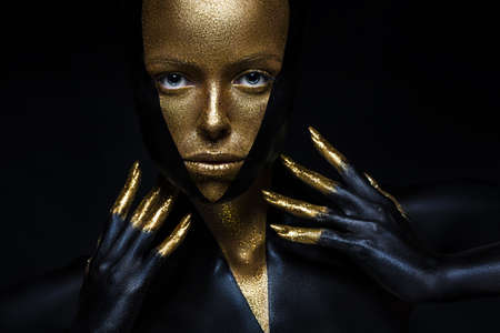 High fashion model with black and gold leather, golden fingers. Isolated on black background Beauty...