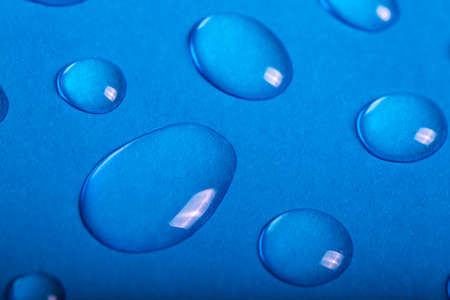 Large drops of water on blue paper. Macrophotography. Abstract backgroundの写真素材