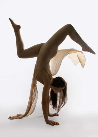 Young beautiful ballerina in a professional outfit performs a dance. Modern ballet. Dancer stands on his handsの写真素材