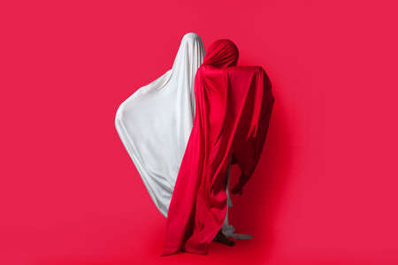 Female figures in fluttering in the wind fabrics. Red and white silhouette on a red background in the Studio. Minimalism. Conceptの写真素材