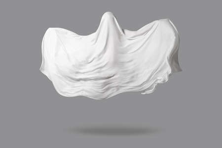 a Ghost in a white fabric fluttering in the wind on a gray background in the Studio. Halloween minimal concept.の写真素材