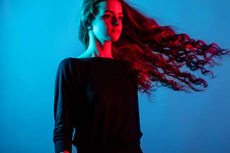 beautiful model with long curly hair in the Studio. Red and blue lighting on the girl. Color filterの写真素材